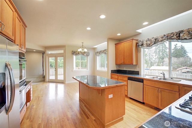 kitchen featuring a kitchen island, light wood-style flooring, french doors, stainless steel appliances, and a sink