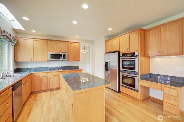 kitchen with light brown cabinetry, tile countertops, light wood-style flooring, appliances with stainless steel finishes, and a sink