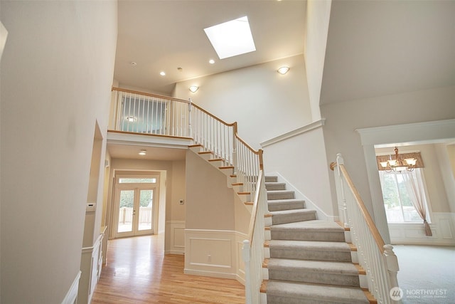 staircase with a decorative wall, plenty of natural light, french doors, and a high ceiling