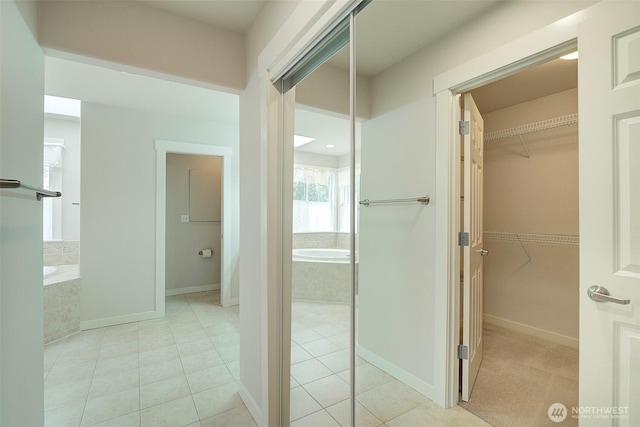 full bathroom with tile patterned floors, a spacious closet, a bath, and baseboards