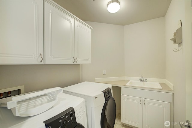 clothes washing area with washer and clothes dryer, cabinet space, and a sink