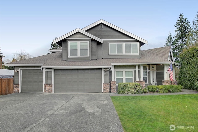 craftsman house with stone siding, concrete driveway, a front yard, and fence