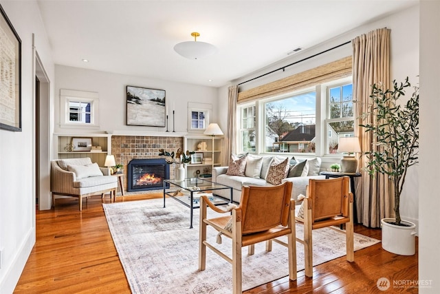 sitting room featuring a fireplace, wood finished floors, visible vents, and baseboards