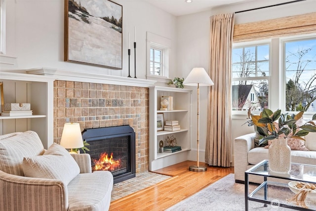 sitting room featuring a brick fireplace and wood finished floors