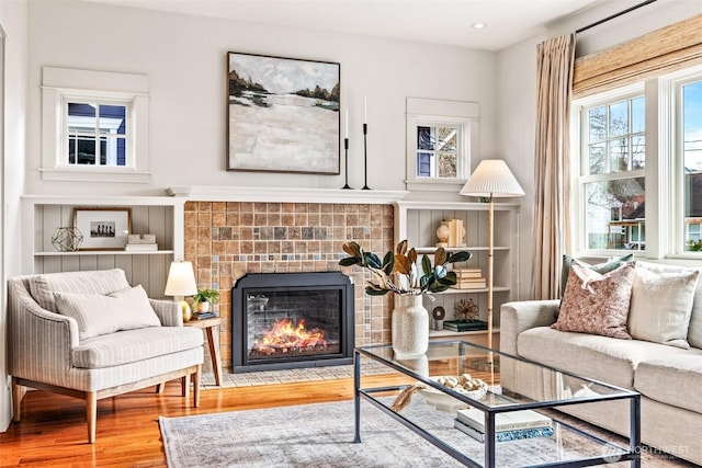 sitting room with a tiled fireplace, wood finished floors, and recessed lighting