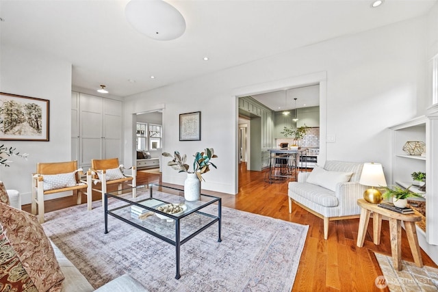 living area featuring light wood-type flooring, baseboards, and recessed lighting