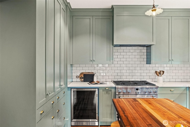 kitchen with beverage cooler, high end range, green cabinets, and decorative backsplash