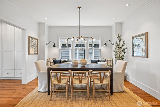 dining room featuring light wood finished floors, baseboards, and crown molding