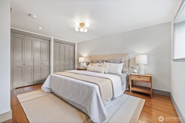 bedroom featuring light wood-style floors, baseboards, and two closets