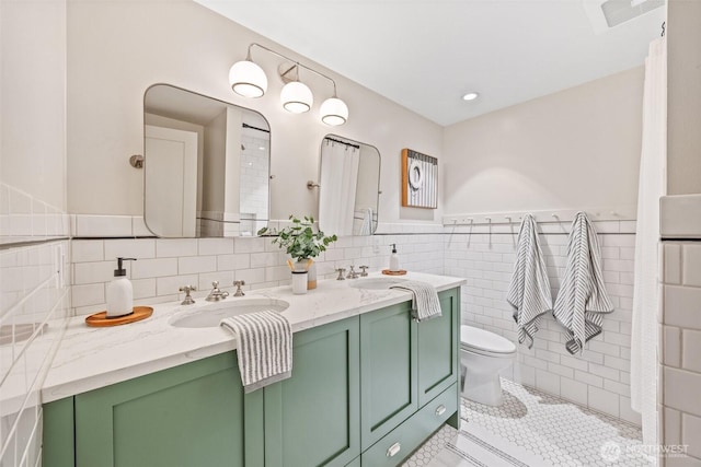 bathroom featuring toilet, tile patterned flooring, double vanity, and a sink