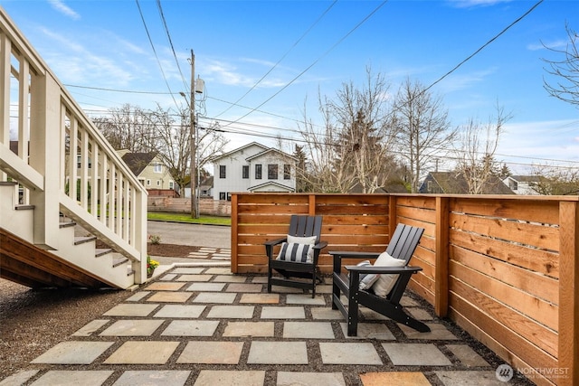 view of patio / terrace with stairs, fence, and a residential view