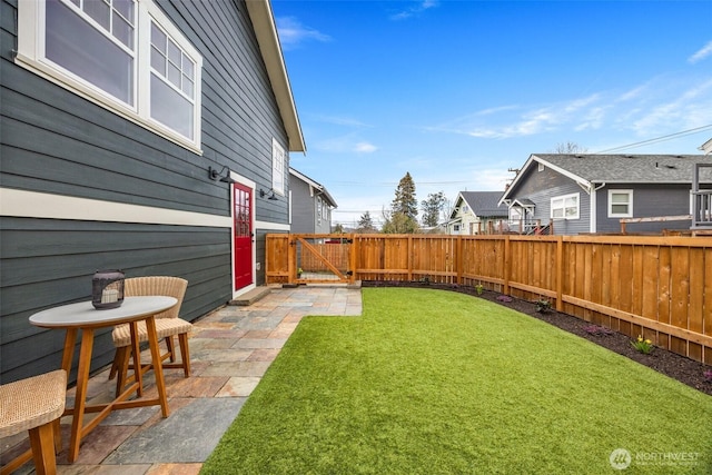 view of yard featuring a gate, a fenced backyard, and a patio