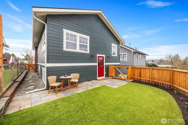 rear view of house with a patio area, a fenced backyard, and a lawn