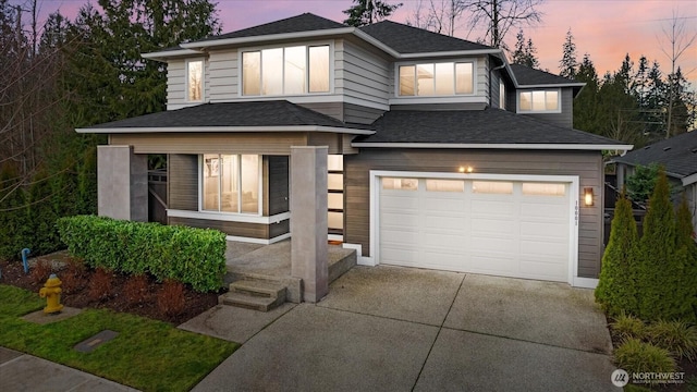 prairie-style home featuring a garage, driveway, and a shingled roof