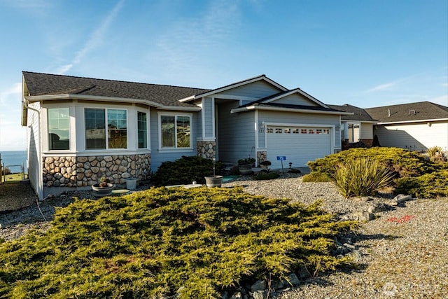 view of front facade featuring a shingled roof, stone siding, and an attached garage