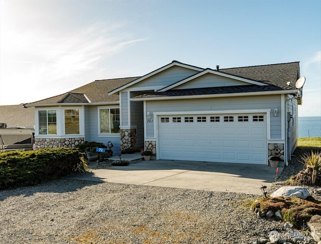 view of front of home with an attached garage, stone siding, concrete driveway, and roof with shingles