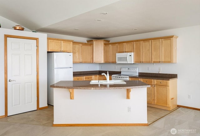 kitchen with white appliances, a breakfast bar area, a sink, and a center island with sink