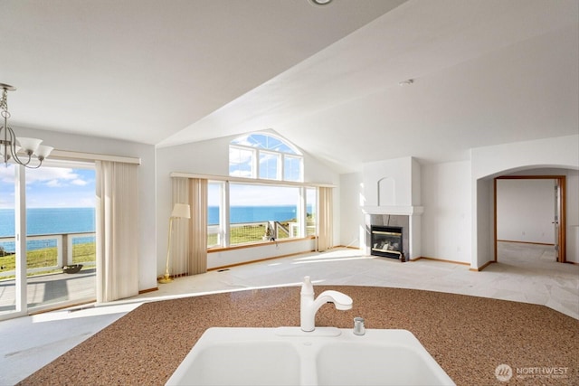 kitchen featuring a water view, plenty of natural light, vaulted ceiling, and a tiled fireplace