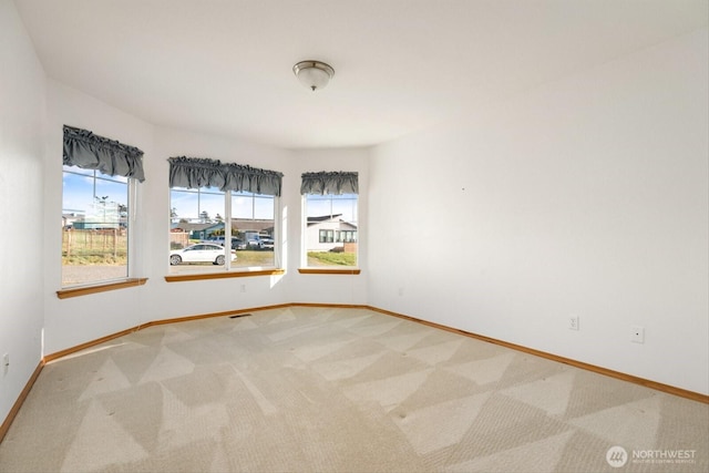 empty room featuring light carpet and baseboards