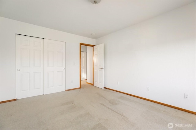 unfurnished bedroom featuring a closet, light colored carpet, and baseboards