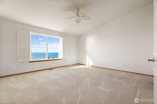 empty room featuring light colored carpet, ceiling fan, visible vents, and baseboards