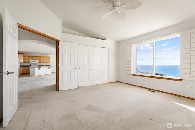 unfurnished bedroom featuring baseboards, visible vents, vaulted ceiling, and light colored carpet