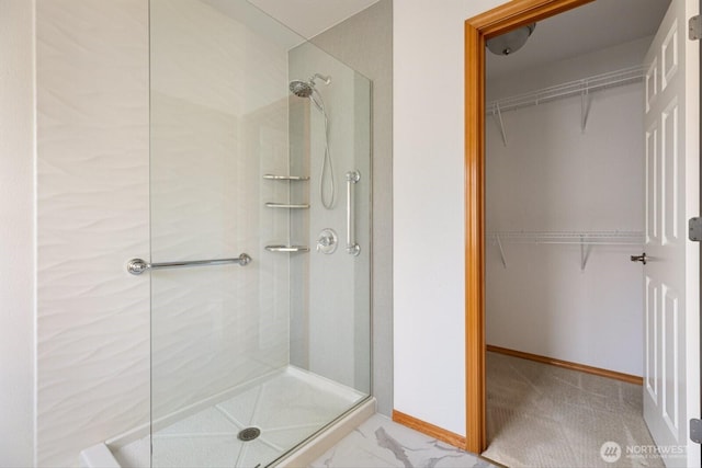 full bath with a stall shower, a walk in closet, and baseboards