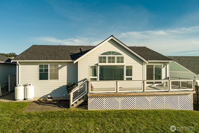 back of house with roof with shingles, a yard, and a wooden deck