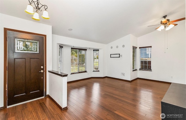 foyer featuring vaulted ceiling, dark wood-style flooring, ceiling fan with notable chandelier, and baseboards