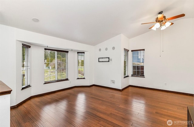 empty room featuring lofted ceiling, ceiling fan, wood finished floors, and baseboards