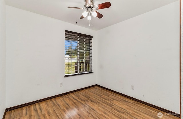 spare room with wood finished floors, a ceiling fan, and baseboards