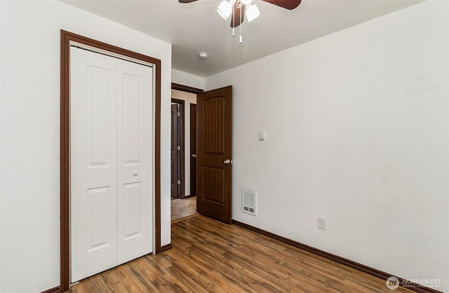 unfurnished bedroom with ceiling fan, visible vents, baseboards, a closet, and dark wood finished floors