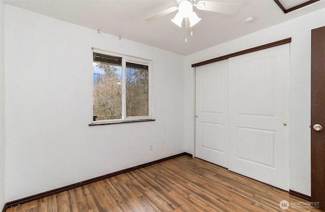 unfurnished bedroom with ceiling fan, a closet, baseboards, and wood finished floors