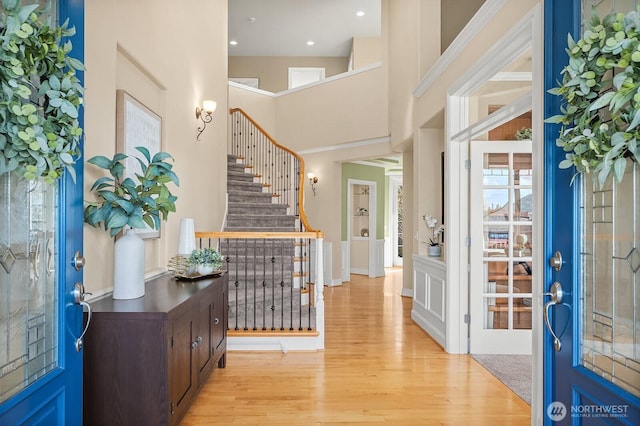 entryway with light wood-style floors, recessed lighting, stairway, and a towering ceiling