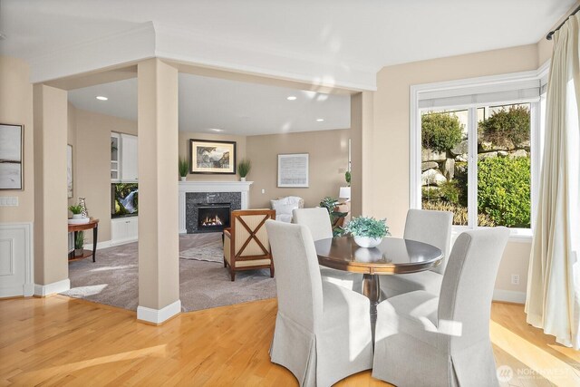 dining room with light wood-style floors, a wealth of natural light, and a high end fireplace