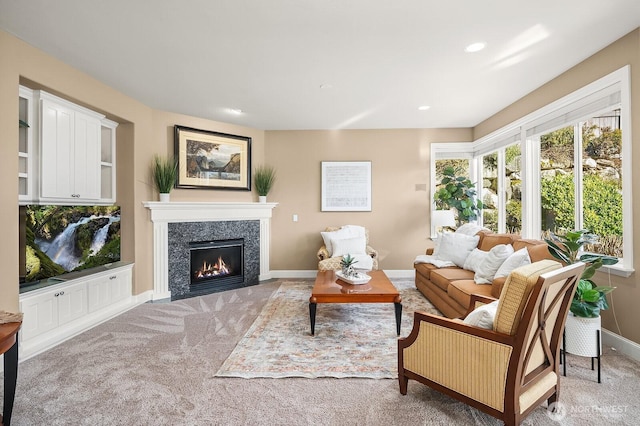 carpeted living area with recessed lighting, a high end fireplace, and baseboards