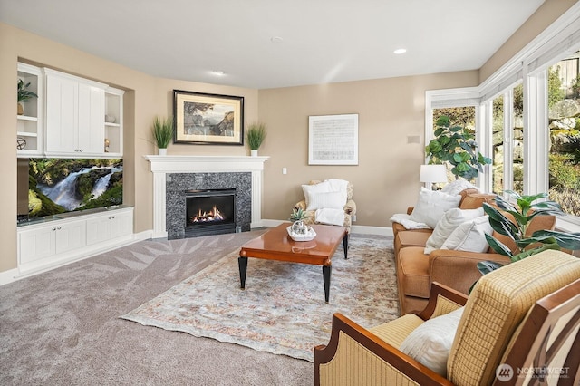 carpeted living room with recessed lighting, a high end fireplace, and baseboards