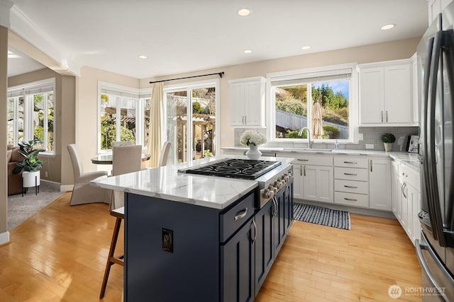 kitchen featuring appliances with stainless steel finishes, a wealth of natural light, white cabinets, and a sink