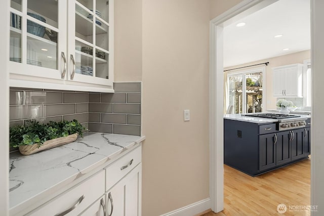 bar with baseboards, decorative backsplash, light wood-style flooring, stainless steel gas stovetop, and recessed lighting