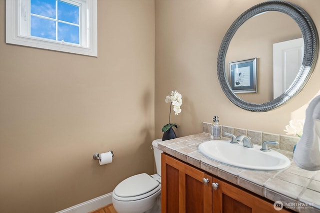 bathroom with baseboards, vanity, and toilet