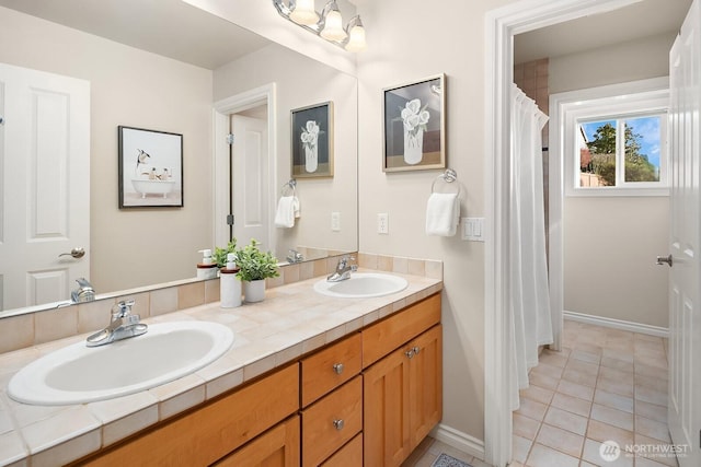 full bathroom with double vanity, baseboards, a sink, and tile patterned floors