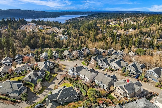 birds eye view of property featuring a forest view, a water view, and a residential view