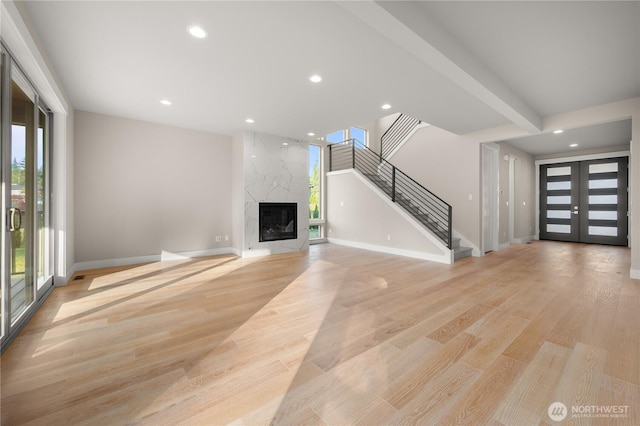 unfurnished living room featuring french doors, stairway, light wood-type flooring, and recessed lighting