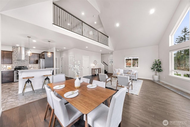 dining room with high vaulted ceiling, hardwood / wood-style floors, recessed lighting, and baseboards