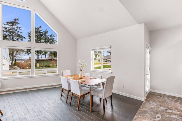 dining area with vaulted ceiling, dark wood-type flooring, and baseboards