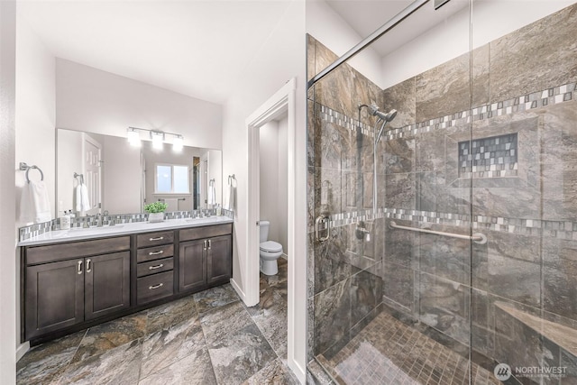 full bathroom featuring double vanity, a stall shower, a sink, and toilet