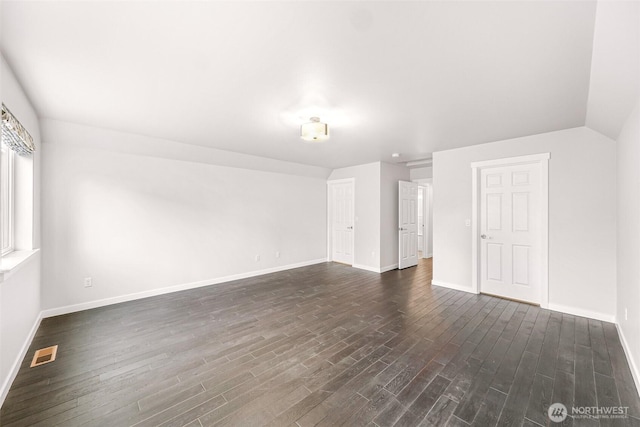 spare room with lofted ceiling, baseboards, visible vents, and dark wood-style flooring