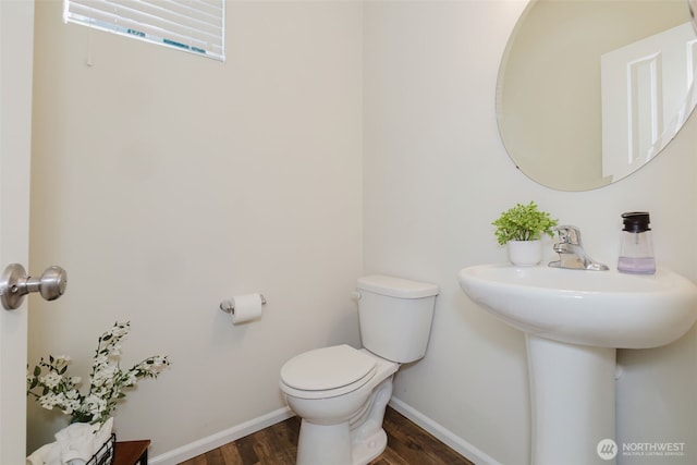 half bathroom featuring toilet, baseboards, and wood finished floors