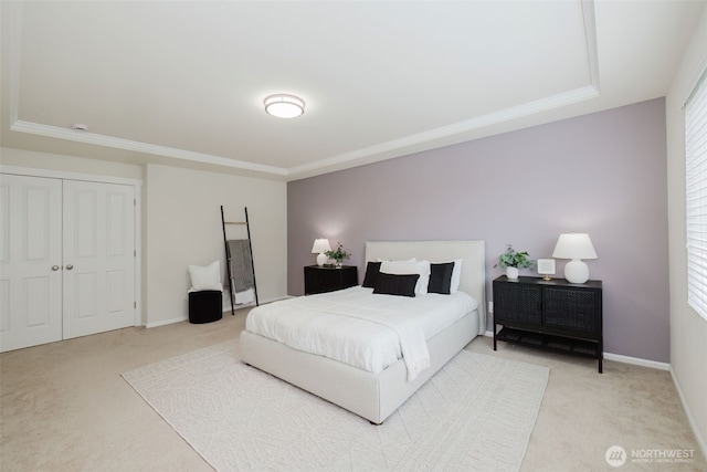 bedroom featuring baseboards, ornamental molding, a closet, and light colored carpet