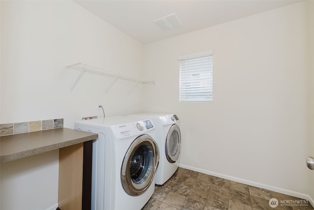 laundry area featuring baseboards, laundry area, stone finish floor, and washer and dryer